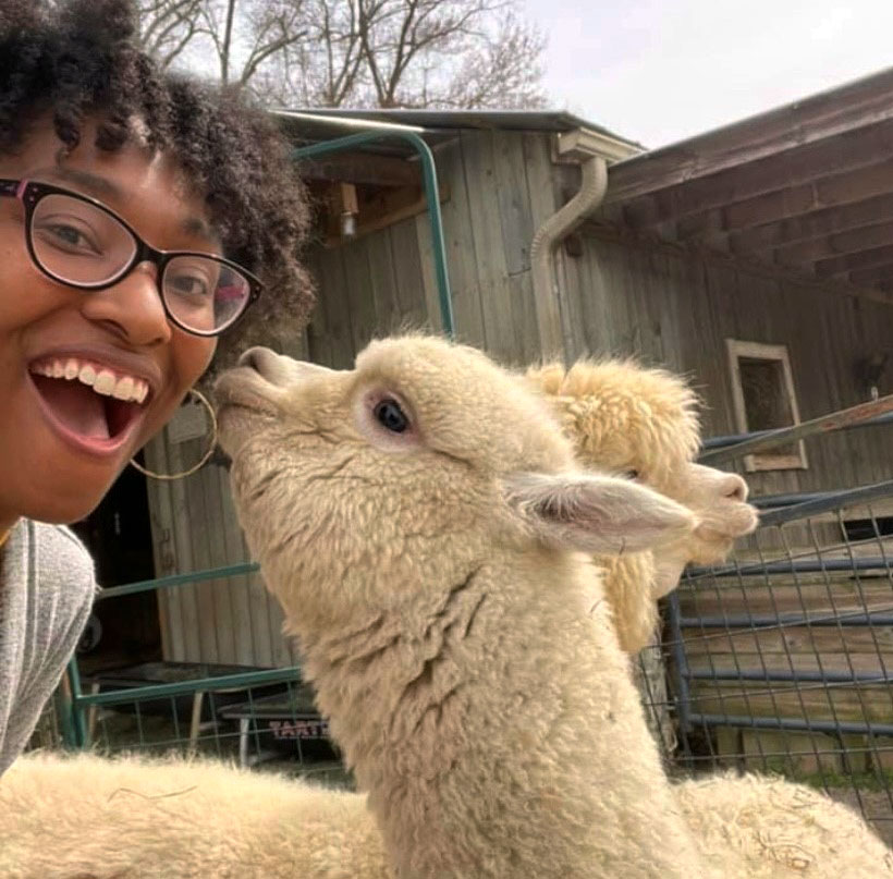 smiling woman up close with an alpaca